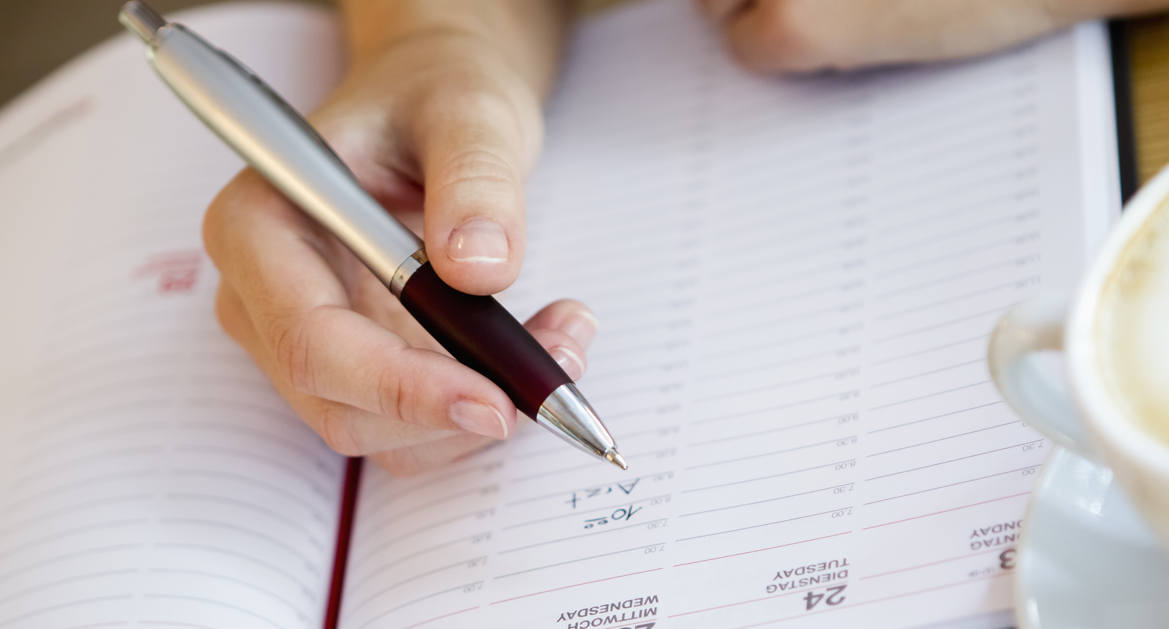 Woman writing in planner with coffee